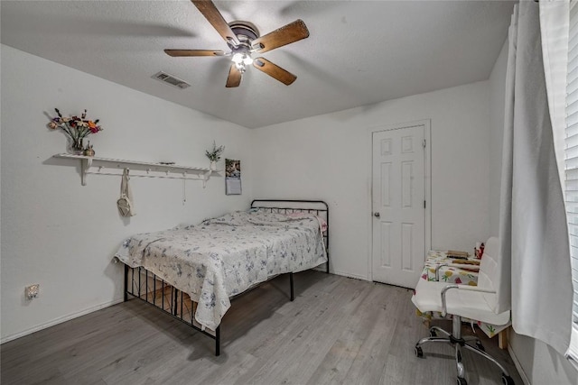 bedroom with hardwood / wood-style flooring, a textured ceiling, and ceiling fan