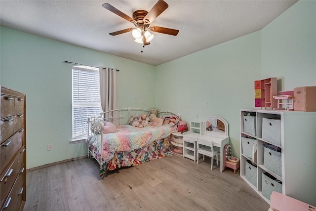 bedroom with a textured ceiling, ceiling fan, and light wood-type flooring