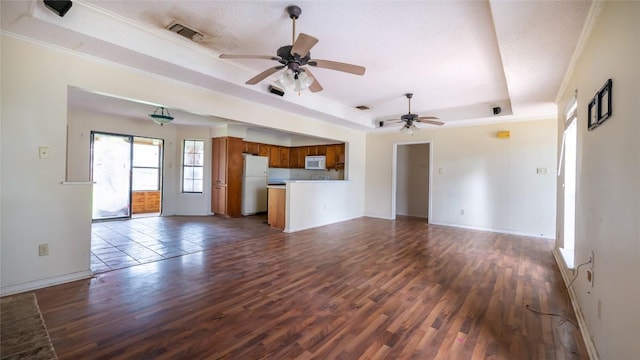 unfurnished living room with a raised ceiling, crown molding, ceiling fan, and dark hardwood / wood-style flooring