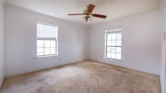 unfurnished room with ceiling fan, a wealth of natural light, light colored carpet, and a textured ceiling