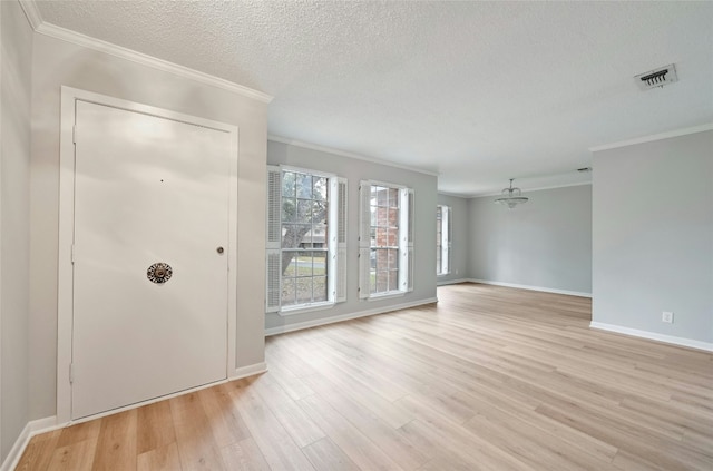 unfurnished room with ornamental molding, a textured ceiling, and light hardwood / wood-style flooring