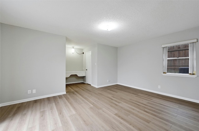 spare room featuring light hardwood / wood-style flooring and a textured ceiling