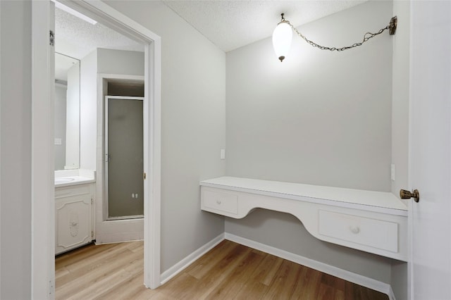 bathroom with an enclosed shower, hardwood / wood-style floors, vanity, and a textured ceiling