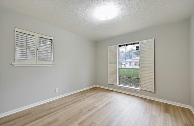 empty room with a textured ceiling and light hardwood / wood-style floors