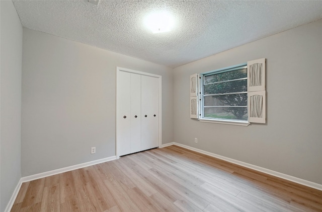 unfurnished bedroom featuring a textured ceiling, light hardwood / wood-style floors, and a closet