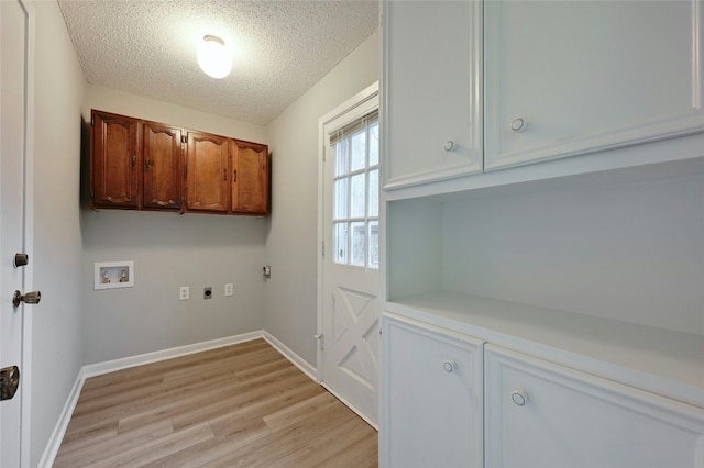 clothes washing area with hookup for a washing machine, cabinets, a textured ceiling, hookup for an electric dryer, and light wood-type flooring