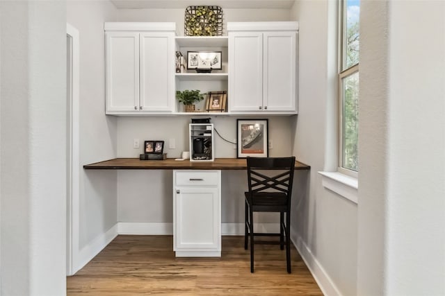 bar featuring white cabinetry, built in desk, wooden counters, and light wood-type flooring