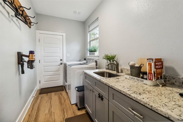 washroom with sink, light hardwood / wood-style flooring, cabinets, and washing machine and clothes dryer