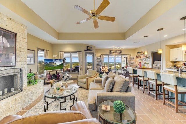 living room featuring ceiling fan, a fireplace, sink, and light tile patterned floors