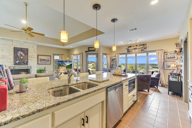 kitchen with a fireplace, built in microwave, sink, stainless steel dishwasher, and light stone counters