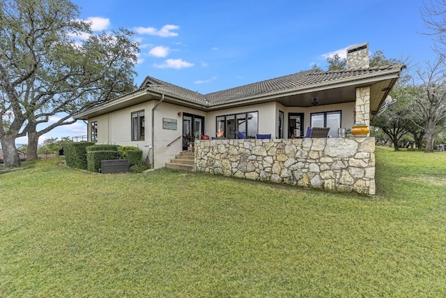 rear view of house featuring ceiling fan and a yard