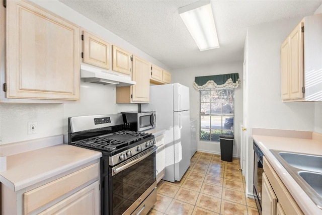 kitchen featuring sink, light tile patterned floors, a textured ceiling, and appliances with stainless steel finishes