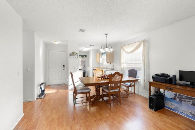 dining room with an inviting chandelier, sink, light hardwood / wood-style floors, and a textured ceiling