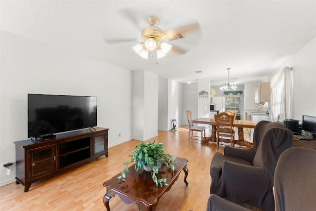 living room with ceiling fan with notable chandelier and light wood-type flooring