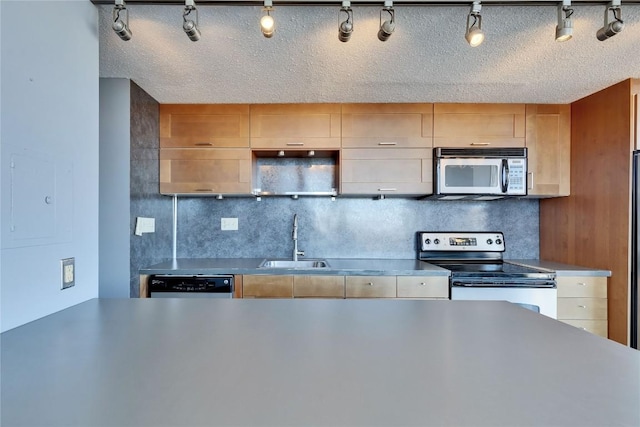 kitchen with appliances with stainless steel finishes, sink, backsplash, and a textured ceiling