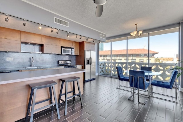 kitchen featuring a breakfast bar, sink, decorative backsplash, stainless steel appliances, and floor to ceiling windows