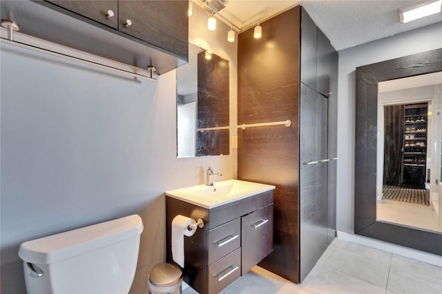 bathroom featuring vanity, toilet, tile patterned flooring, and a textured ceiling