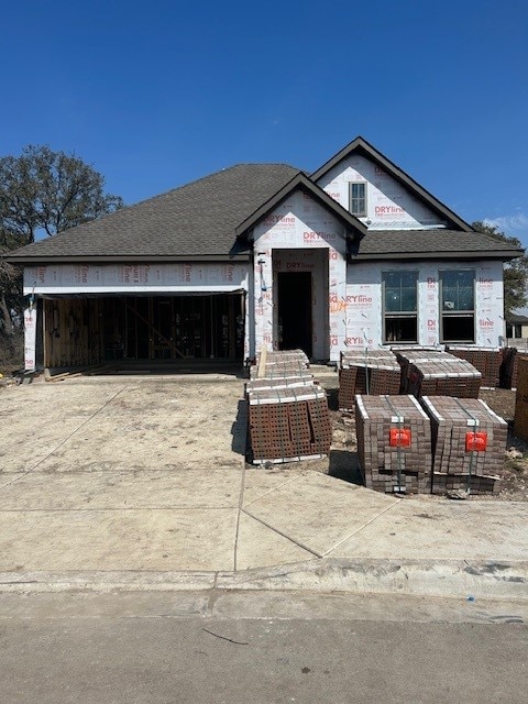 property in mid-construction featuring a garage, driveway, and a shingled roof