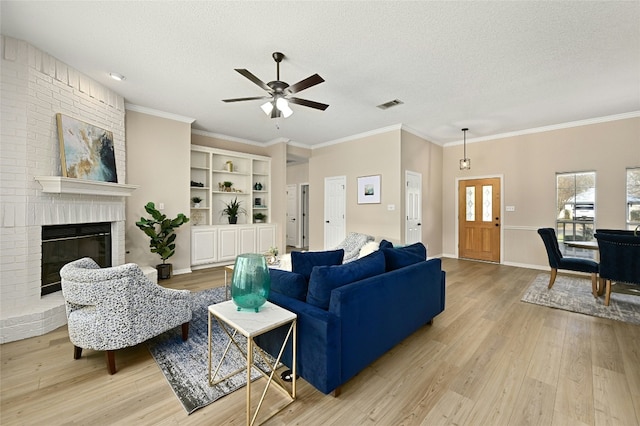 living room featuring crown molding, a fireplace, light hardwood / wood-style floors, and a textured ceiling