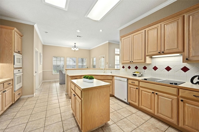 kitchen with crown molding, white appliances, sink, and a kitchen island