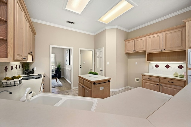 kitchen featuring sink, crown molding, a center island, tasteful backsplash, and light brown cabinetry