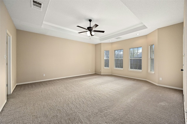 carpeted empty room with ceiling fan, a raised ceiling, and a textured ceiling