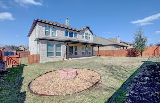 rear view of property with a fire pit and a lawn