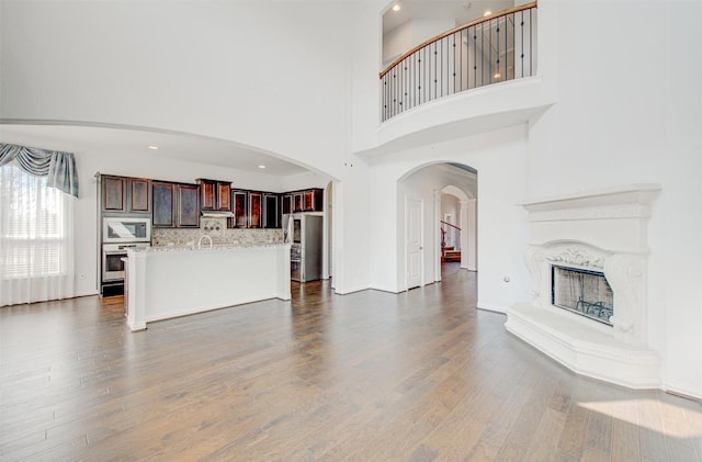 unfurnished living room featuring a premium fireplace, dark hardwood / wood-style floors, and a towering ceiling