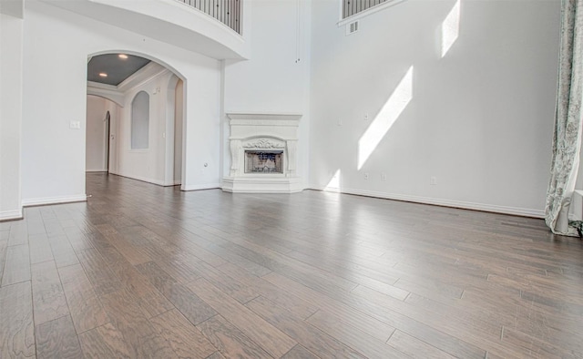 unfurnished living room with a premium fireplace, hardwood / wood-style floors, and a high ceiling