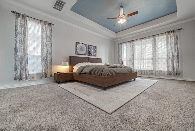 carpeted bedroom featuring crown molding, ceiling fan, and a tray ceiling