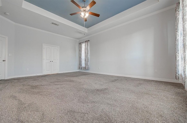 carpeted empty room with crown molding, a raised ceiling, and ceiling fan