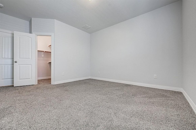 interior space with lofted ceiling, a spacious closet, a textured ceiling, a closet, and carpet