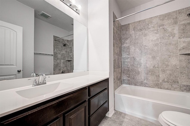 full bathroom featuring toilet, a textured ceiling, vanity, tiled shower / bath combo, and tile patterned flooring