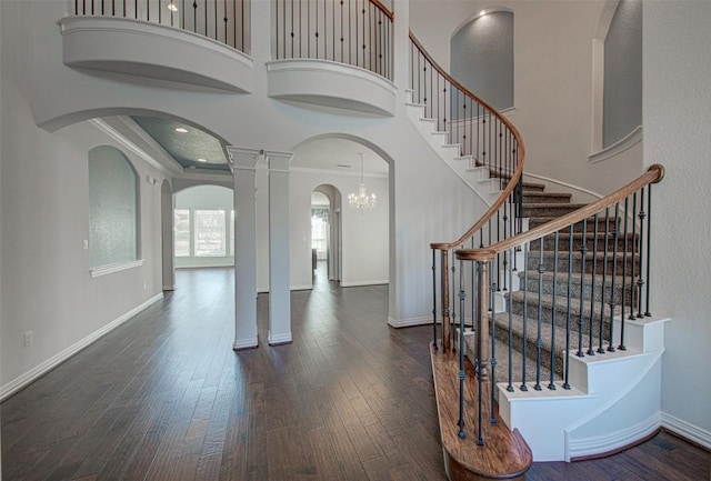 entrance foyer featuring crown molding, decorative columns, dark hardwood / wood-style floors, and a high ceiling