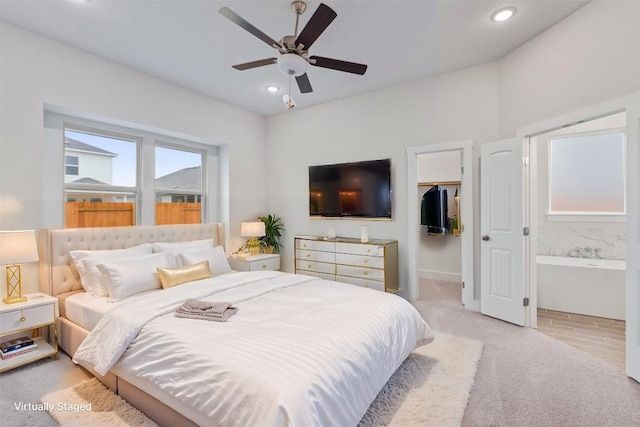 bedroom with ensuite bath, a spacious closet, light carpet, a closet, and ceiling fan