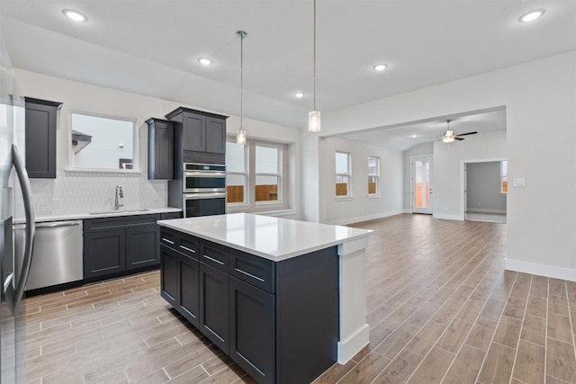 kitchen with sink, hanging light fixtures, stainless steel appliances, a center island, and tasteful backsplash