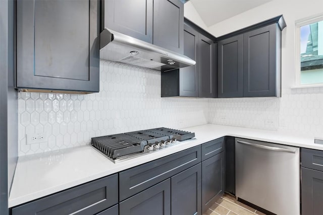 kitchen with tasteful backsplash, appliances with stainless steel finishes, gray cabinetry, and wall chimney range hood