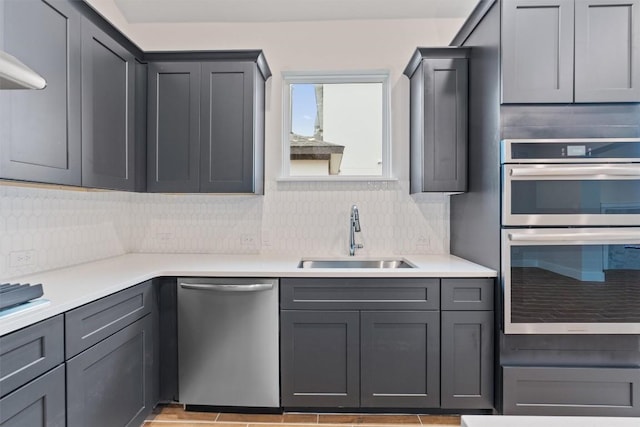 kitchen with stainless steel appliances, sink, backsplash, and gray cabinets