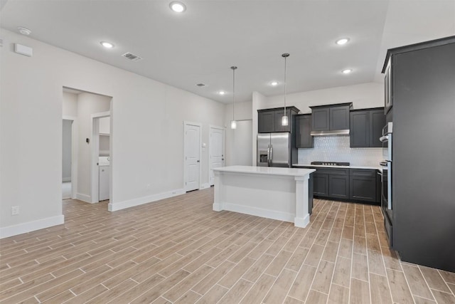 kitchen with decorative light fixtures, stainless steel fridge with ice dispenser, a kitchen island, black gas cooktop, and backsplash