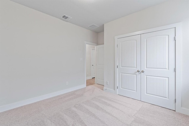 unfurnished bedroom with a closet and light carpet