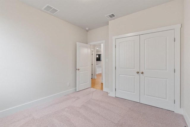 unfurnished bedroom featuring a closet and light carpet