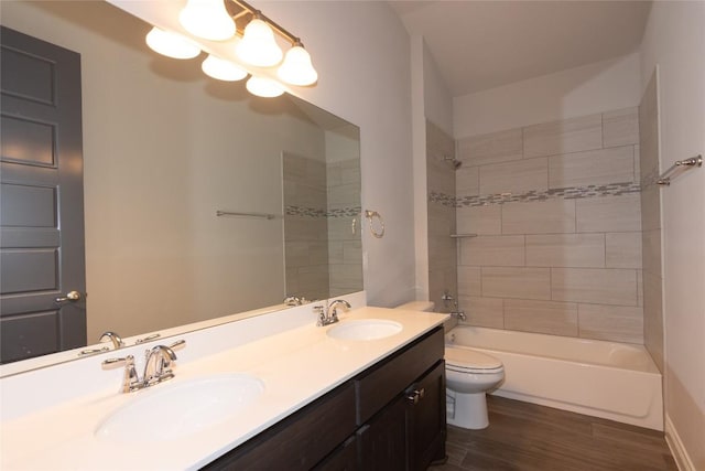 full bathroom featuring vanity, tiled shower / bath combo, wood-type flooring, and toilet