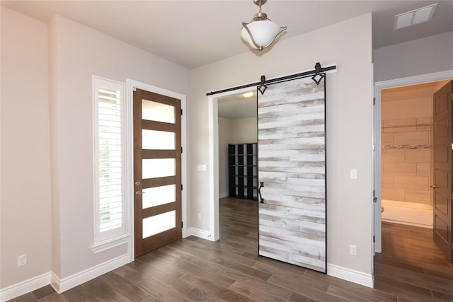 foyer with dark wood-type flooring and a barn door