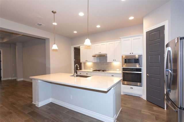 kitchen with appliances with stainless steel finishes, sink, hanging light fixtures, and a center island with sink