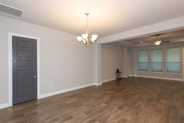 empty room with dark wood-type flooring, a raised ceiling, and ceiling fan with notable chandelier