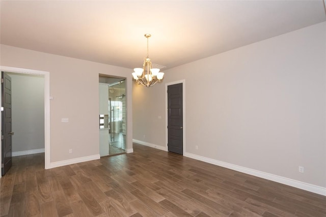 spare room featuring dark hardwood / wood-style flooring and a chandelier