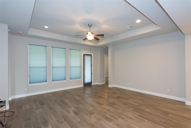 unfurnished room with a raised ceiling, hardwood / wood-style floors, and ceiling fan