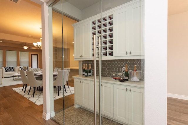 bar featuring white cabinetry, light hardwood / wood-style flooring, pendant lighting, ceiling fan, and decorative backsplash