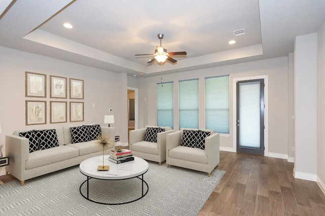 living room featuring a tray ceiling, ceiling fan, and hardwood / wood-style flooring