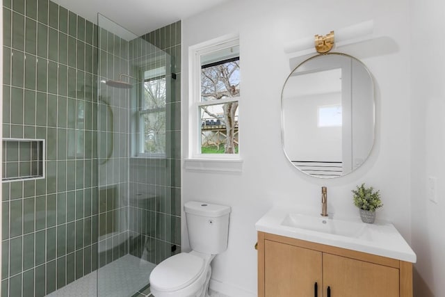 bathroom featuring vanity, a healthy amount of sunlight, a tile shower, and toilet